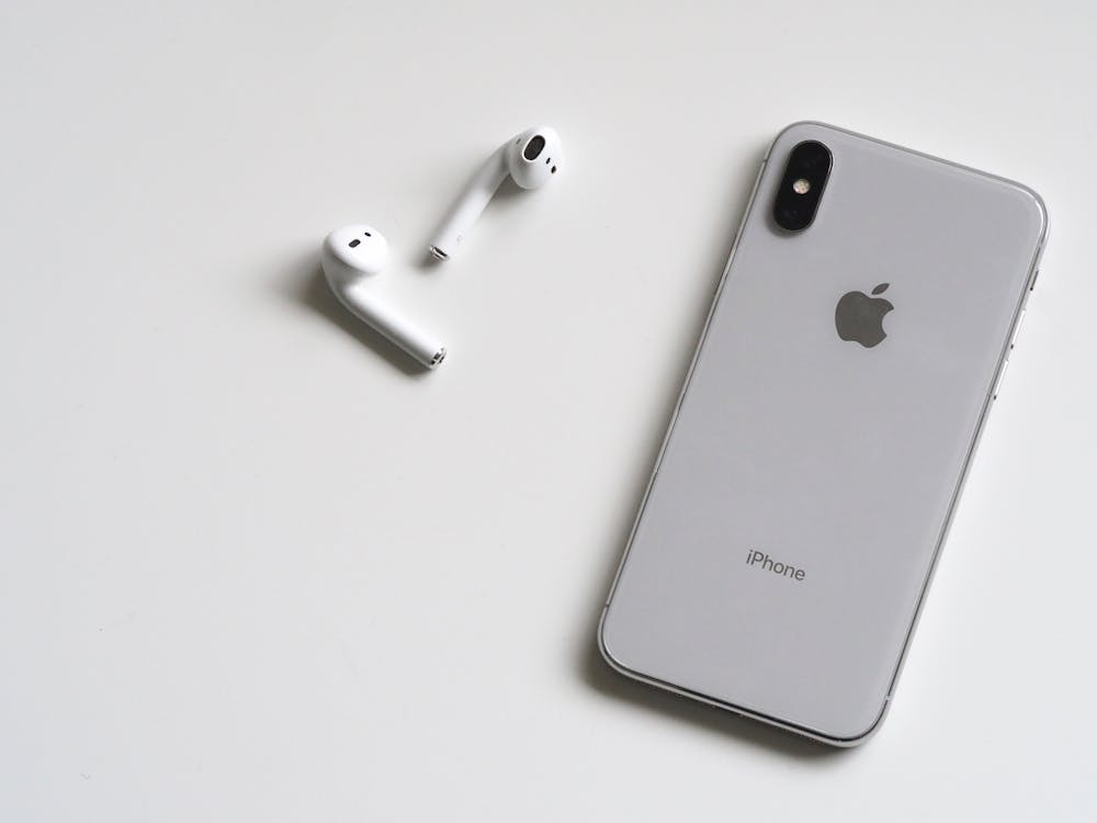 iPhone on white desk showing Apple services — Apple One subscription 2026