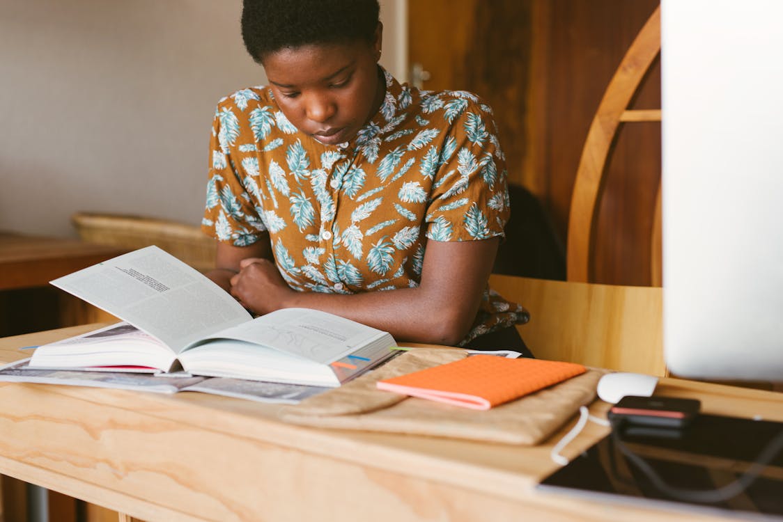 Woman reading personal finance books at desk — best books for financial education 2026