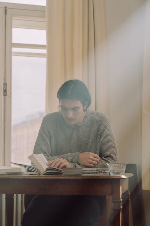 Man reading personal finance book at desk by window — financial education 2026
