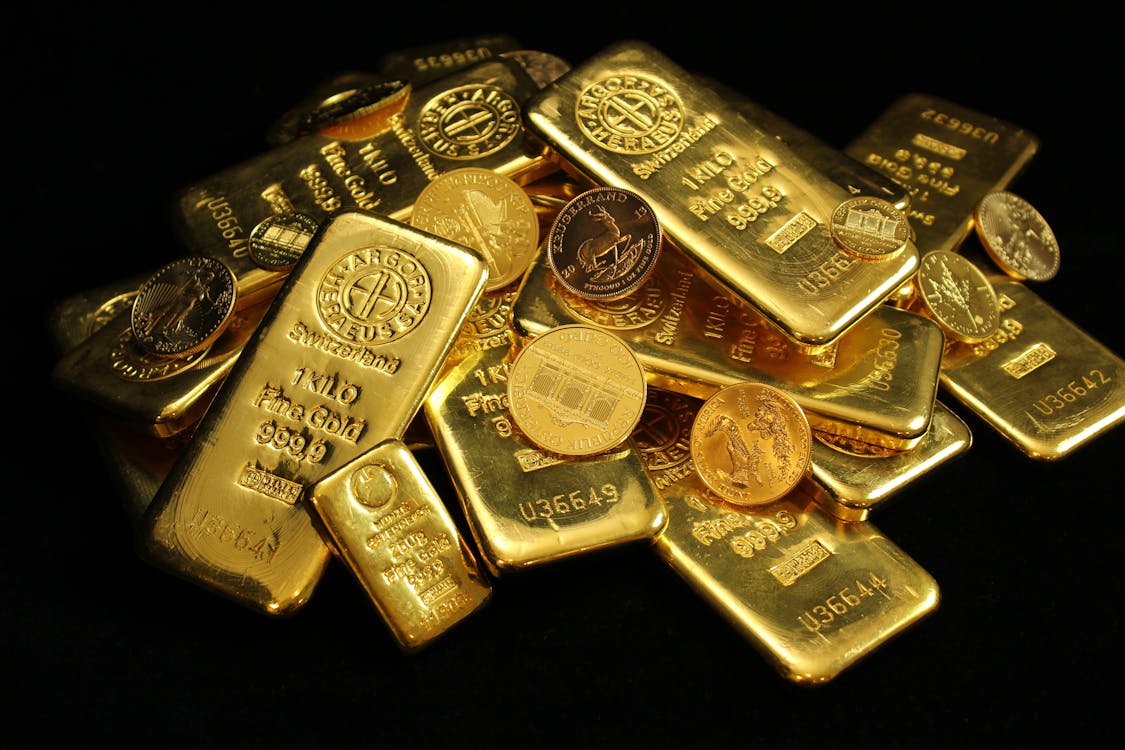 Gold coins and bars on dark background — physical gold investment 2026
